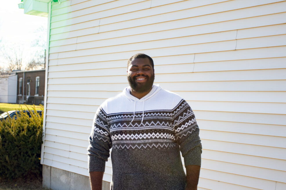 Picture of male smiling in neighborhood wearing a sweater