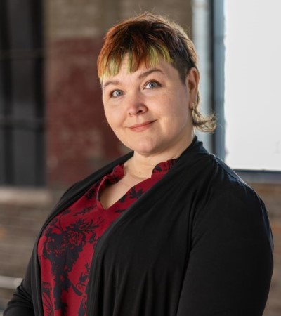 Portrait of female wearing black jacket and red shirt.